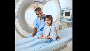 Un niño de aproximadamente 6 años, de ascendencia hispana, sentado en una cama de hospital en una sala de imágenes médicas moderna. Lleva una bata de hospital azul claro y observa con curiosidad una máquina de resonancia magnética avanzada. Un radiólogo hispano le explica el procedimiento, creando un ambiente de apoyo y tranquilidad, destacando la importancia de la detección temprana del meduloblastoma en el diagnóstico pediátrico.